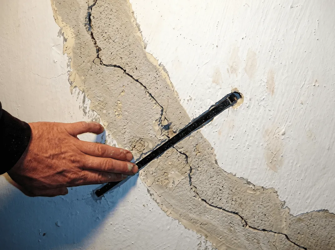 A wall with a large crack is being inspected by a professional in Sacramento, CA